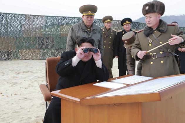 Handout photo of North Korean leader Kim Jong Un looking through a pair of binoculars as he guides the multiple-rocket launching drill of women's sub-units under KPA Unit 851